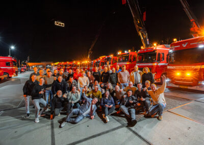 Team van Verwaal Transport poseert uitgelaten in de avond voor het verlichte wagenpark tijdens het Hofleverancier-feest